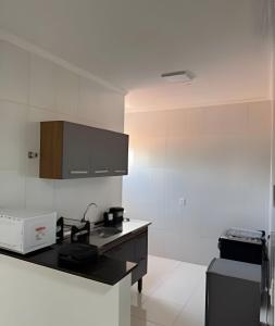 a kitchen with white walls and a black counter top at Abaíra Serra Azul Loft 5 - Orla - Centro in Petrolina +15 photos