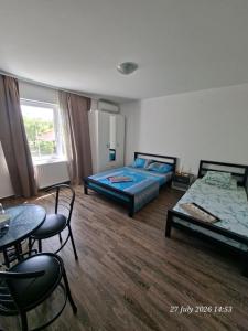 a bedroom with two beds and a table and chairs at EasyHedonist in Stara Pazova