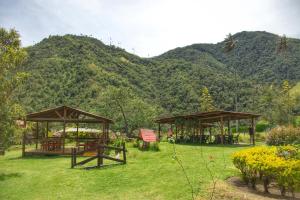 a park with two picnic tables and a mountain at Palmas de Cocora in Salento +33 photos