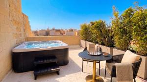a hot tub on a patio with a table at St Anne Palace by Tritoni Prestige in Il-Furjana