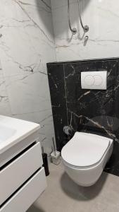 a bathroom with a white toilet and a sink at Hidden Hills Cottage Sarajevo in Sarajevo