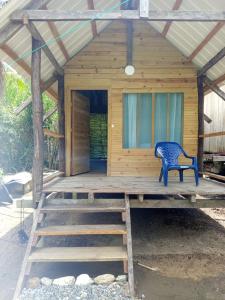 a wooden cabin with a blue chair on the porch at Cabaña Vikana in Nuquí