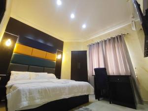 a bedroom with a bed and a desk and a window at IBK's Hotels and Suites in Rumuola