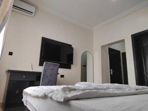 a bedroom with a bed and a flat screen tv at IBK's Hotels and Suites in Rumuola