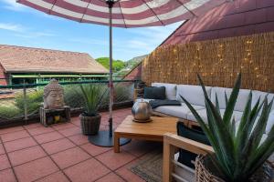 a patio with a couch and an umbrella at Schwarzwaldloge Zeitlos in Sasbachwalden