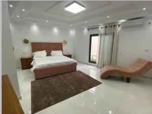 a bedroom with a bed and a bench and a window at m hadji premium in Dakar
