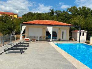 a swimming pool with chairs next to a house at Holiday Sparks in Jadranovo