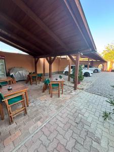 a patio with tables and chairs under a roof at Két Sirály Apartman in Siklós