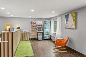 a kitchen with an orange chair and a refrigerator at Spark By Hilton Prestonsburg in Prestonsburg