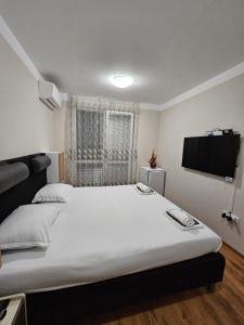 a bedroom with a large white bed and a flat screen tv at Apartments Vilma&Villiam in Ravda +15 photos