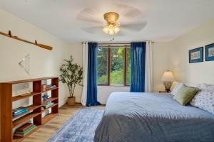 a bedroom with a bed and a window with blue curtains at Steps to Beach: Martha's Vineyard Private Retreat! in Vineyard Haven