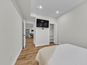 a white bedroom with a bed and a flat screen tv at Windsor Perfect Stay in Windsor