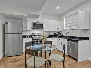 a kitchen with white cabinets and a glass table and chairs at Windsor Perfect Stay in Windsor