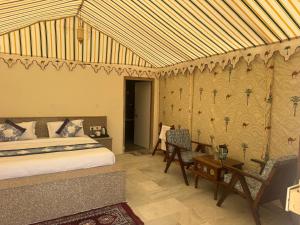 a bedroom with a bed and a table and chairs at Mahindra Desert Resort & Camp in Jaisalmer +40 photos