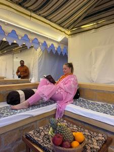 a woman sitting on a bed in a tent at Mahindra Desert Resort & Camp in Jaisalmer