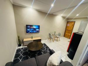 a living room with a couch and a tv at Hei Stays One Bed Apartment in Bronkhorstspruit