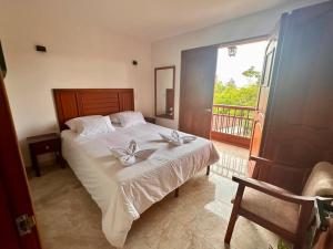 ein Schlafzimmer mit einem Bett mit weißen Laken und einem Balkon in der Unterkunft Los Barranqueros Hotel in Salento + 12 Fotos