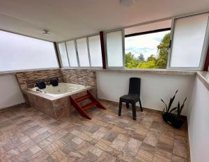 ein Badezimmer mit Badewanne, Stuhl und Fenstern in der Unterkunft Los Barranqueros Hotel in Salento