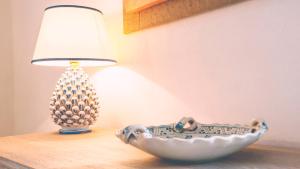 a lamp and a bowl sitting on a table next to a lamp gmaxwell gmaxwell at Chibedda Dimora Lia in Acitrezza