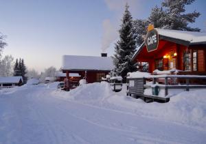 una casa cubierta de nieve junto a una carretera cubierta de nieve en Peurasuvanto Mökit & Camping, en Peurasuvanto