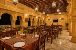 a dining room with tables and chairs and chandeliers at Mahindra Desert Resort & Camp in Jaisalmer