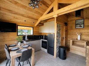 a kitchen with a dining table in a cabin at Les 2 Chalets Alpins & Bains Nordiques in Saint-Michel-de-Chaillol
