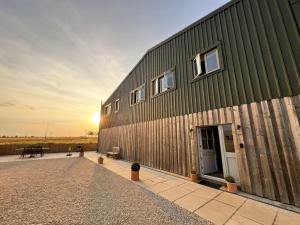 a large green building with a sunset in the background at The Hayloft in Calne