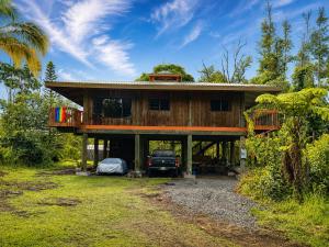 a house with a truck parked in front of it at Tiki Treehouse in Keaau
