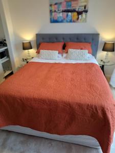 a bedroom with a large bed with an orange blanket at Kupe Retreat free wifi free parking two rooms ensuite bathroom for both in Whitianga