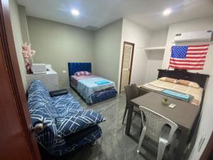 a room with two beds and a table and a bed and a chair at Hospedaje Blue House - Consulado americano - Habitacion 2 in Guayaquil
