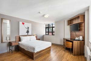 a bedroom with a bed and a desk and a television at The Mitre Hotel Brighton in Brighton & Hove