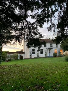 a white house with a green yard at 5-bed house with indoor pool, Jacuzzi &Downs views in Herstmonceux