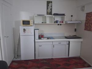 a small kitchen with a white refrigerator and a microwave at Logement meublé proche CHUM, idéal stagiaires et professionnels in Le Lamentin +5 photos
