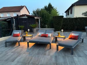 a patio with two chairs and two tables with red pillows at Studio piscine in Puy-Guillaume
