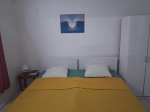 a bedroom with a bed with a yellow blanket on it at Logement meublé proche CHUM, idéal stagiaires et professionnels in Le Lamentin