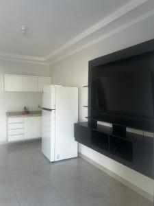 a kitchen with a white refrigerator and a flat screen tv at Florence Nightingale in Sorriso