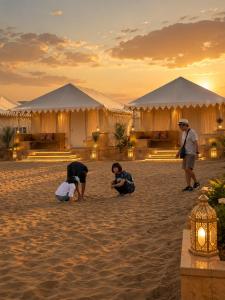 a group of people on the beach in front of tents at Mahindra Desert Resort & Camp in Jaisalmer