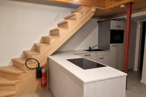 a kitchen with white countertops and wooden stairs at Eiflia- Im Ourtal in Burg-Reuland
