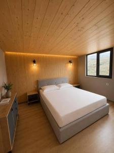 a bedroom with a large bed with a wooden ceiling at Highland Hils in Garni +2 photos