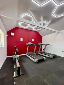 a gym with a red wall and two tread machines at Pebbles holidays in Sandown