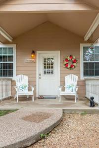 two white chairs on the front porch of a house at Cozy Cottage in Waco