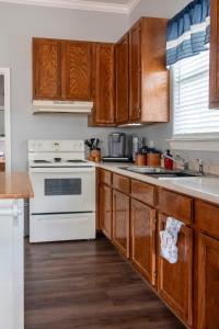 a kitchen with wooden cabinets and a white stove top oven at Cozy Cottage in Waco