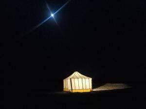 a white tent is lit up in the dark at Kidal Luxury Camp in Adrouine