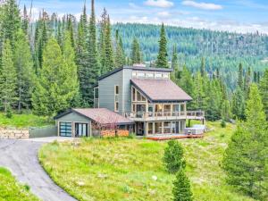 a large house on a grassy hill with trees at Lone Mountain Lookout in Big Sky