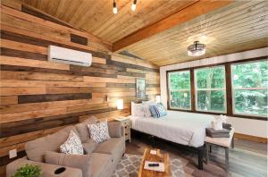 a bedroom with wooden walls and a bed and a couch at Tiny Tarheel Cozy Retreat Near UNC-Tiny House in Chapel Hill