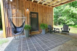 a porch with a hammock and two chairs and a house at Tiny Tarheel Cozy Retreat Near UNC-Tiny House in Chapel Hill