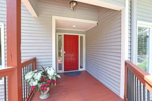 a red door on a house with a vase of flowers at Lg Pool House w Hot Tub Central to RTPPool OPEN in Durham