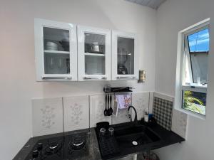 a kitchen with a sink and white cabinets at Aura Mar Flat in Baía Formosa