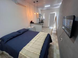 a bedroom with a bed and a television and a kitchen at Aura Mar Flat in Baía Formosa