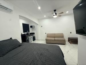 a bedroom with a bed and a couch and a ceiling fan at Lujoso departamento con alberca y jacuzzi in Monterrey